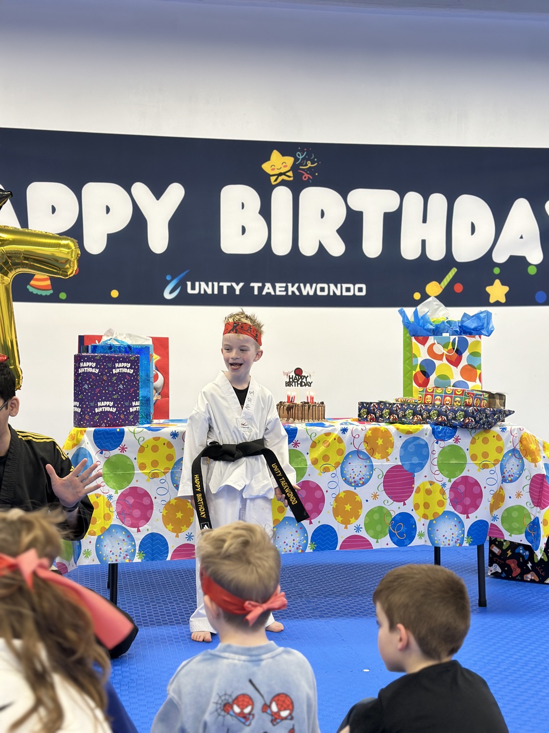 Birthday child in uniform presenting in front of the Happy Birthday banner at Unity Taekwondo Chilliwack