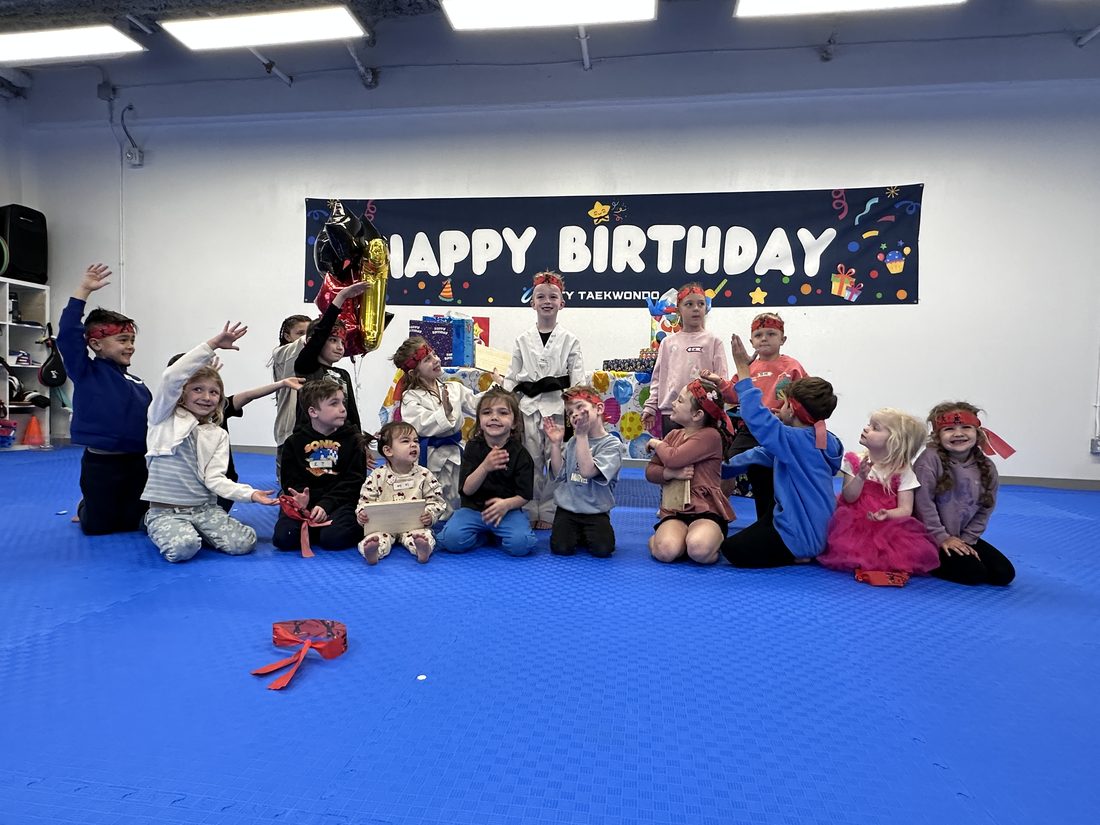 Group of children cheering in front of the Happy Birthday banner at Unity Taekwondo Chilliwack