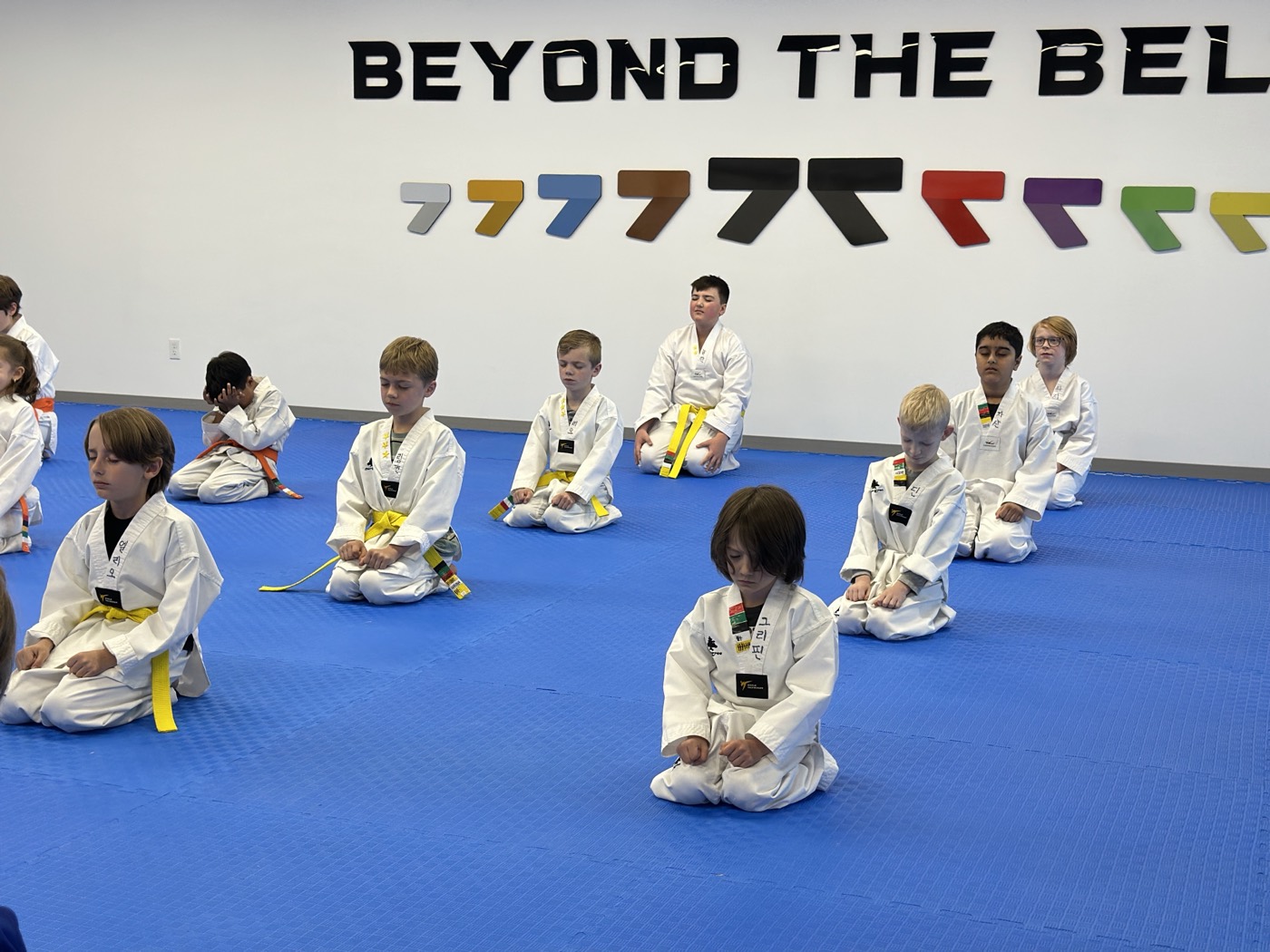 Unity Taekwondo students kneeling in focused meditation at the start of a kids' class in Chilliwack, BC
