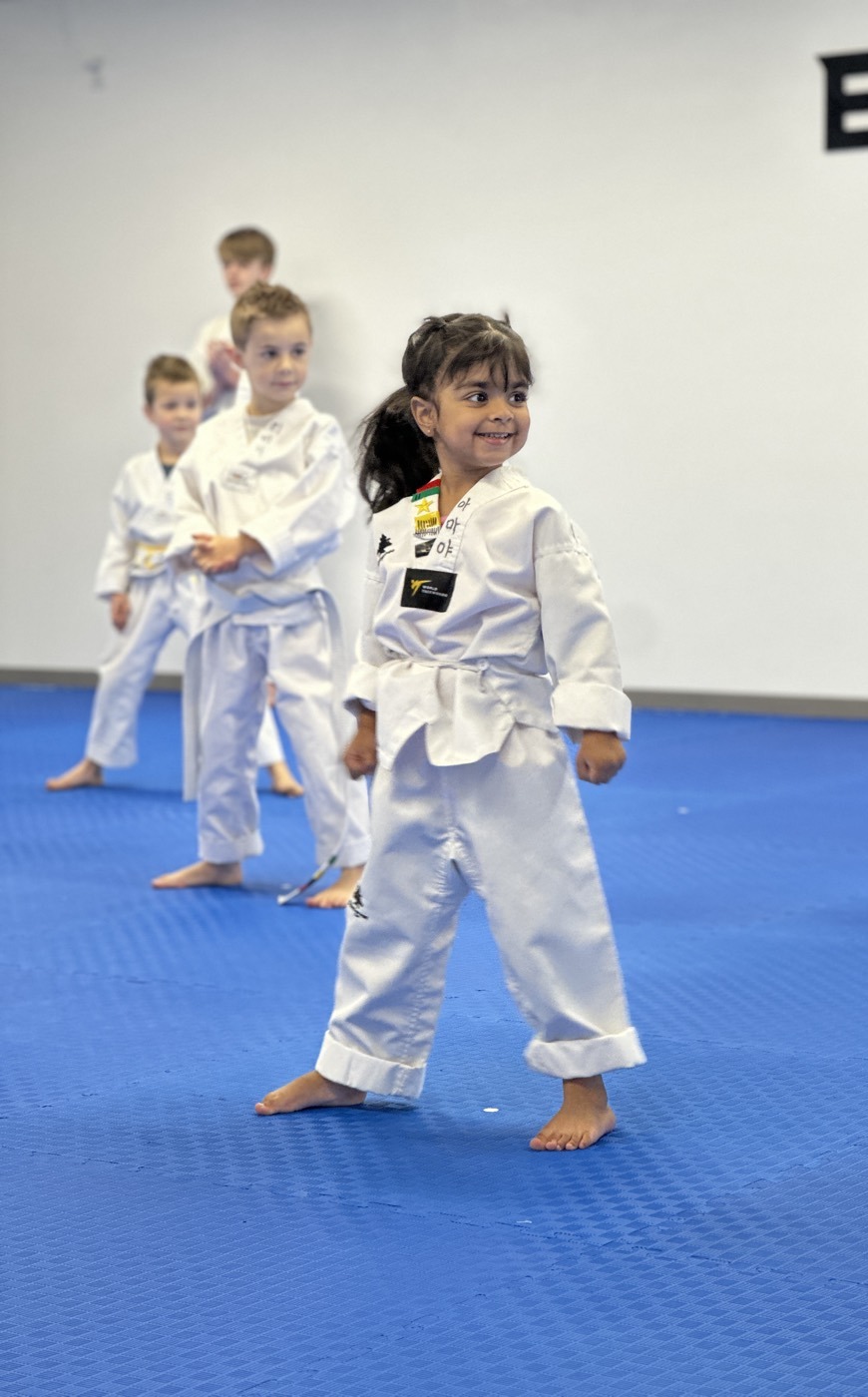 A young Unity Taekwondo student smiling confidently during a kids' class in Chilliwack, BC