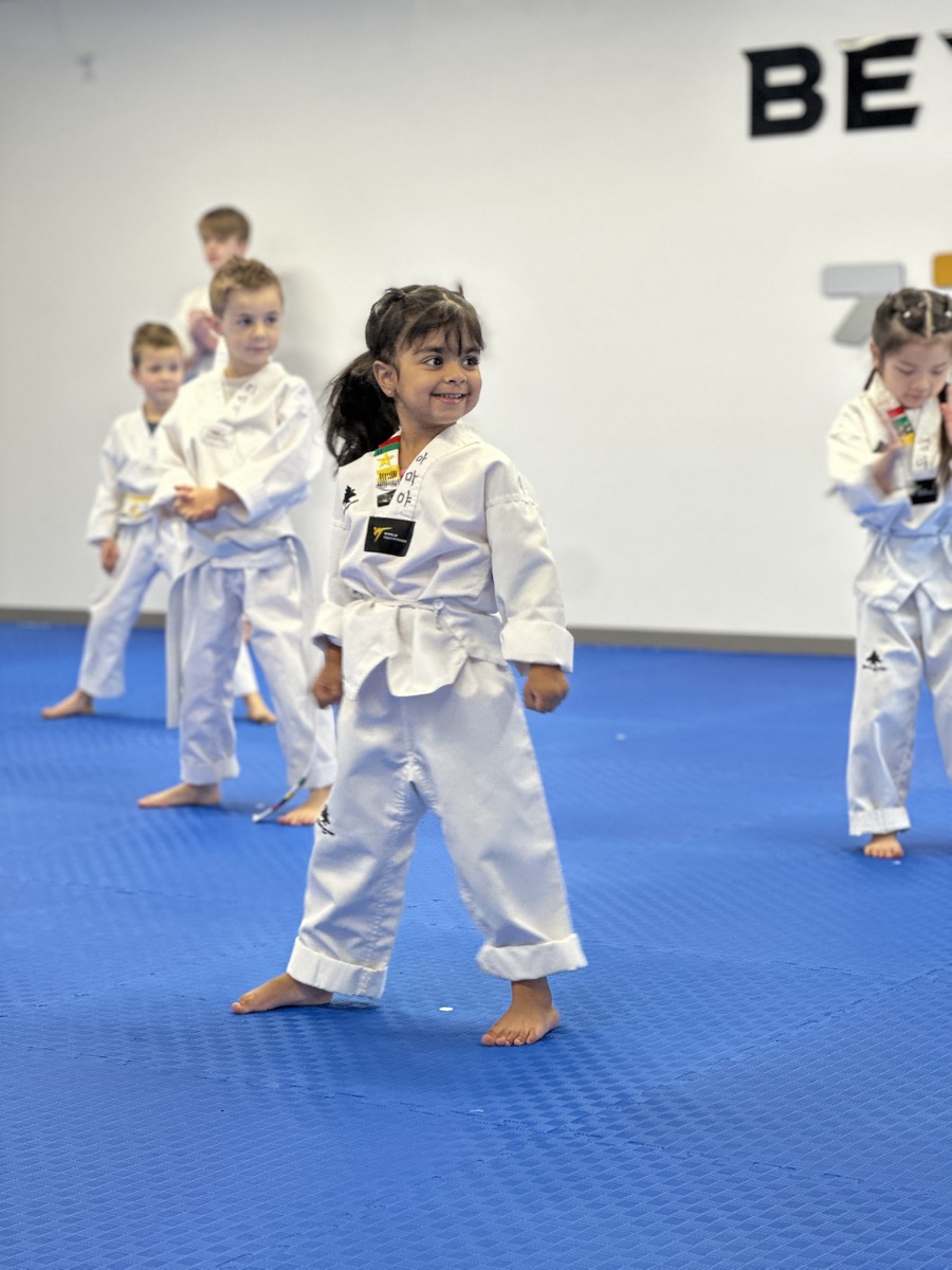 Master Nam guiding a young U-Star student through a kick at Unity Taekwondo